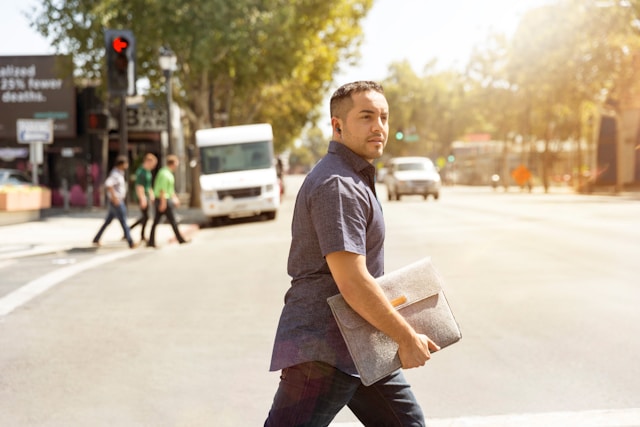 homme marchant dans la rue avec une pochette grise à la main